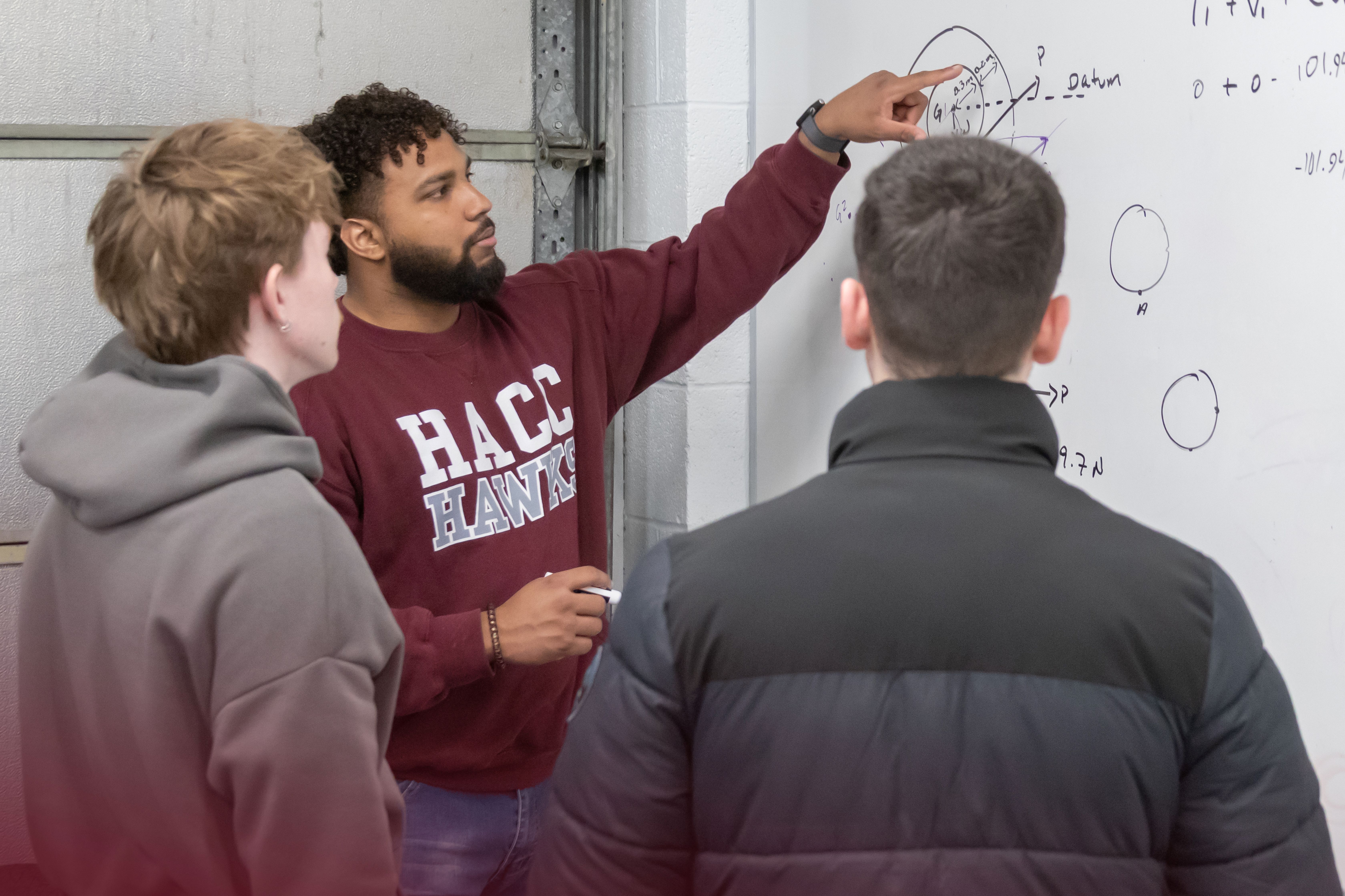 HACC engineering student writing on a whiteboard
