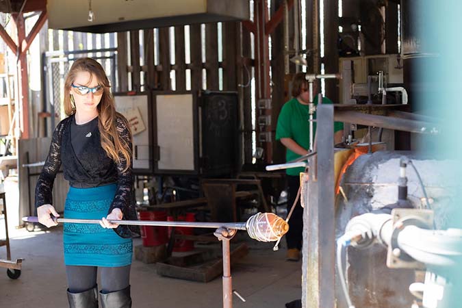 Student with molten glass at furnace